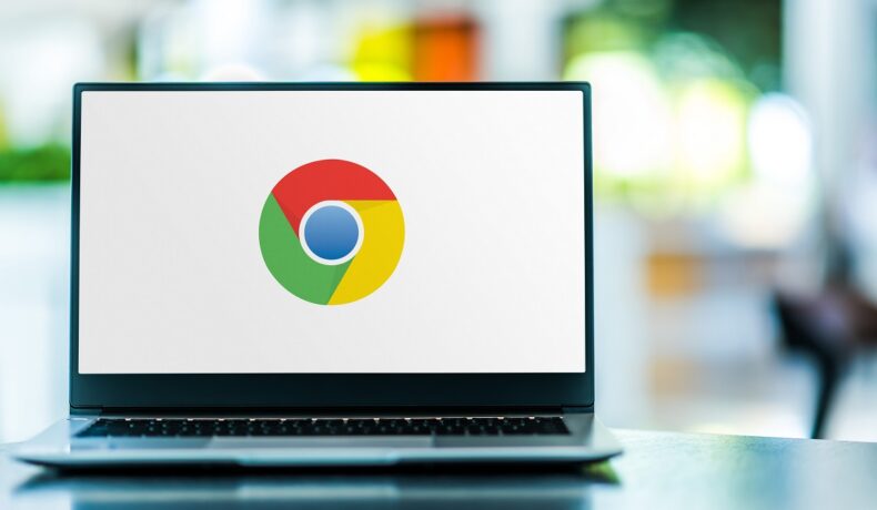Logo-ul Google pe ecranul unui laptop, fundalul alb. Laptopul e gri, pe masă. Google a emis un avertisment recent pentru utilizatorii Chrome