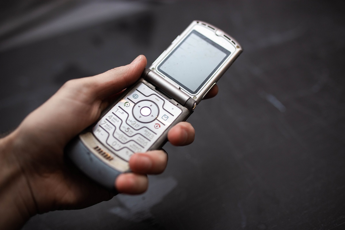 Motorola Rarz V3 pe argintiu, în mâna unui utilizator, cu fundal gri spre negru. Motorola Razr V3 e un telefon flip. E unul dintre cele mai vândute telefoane mobile din istorie
