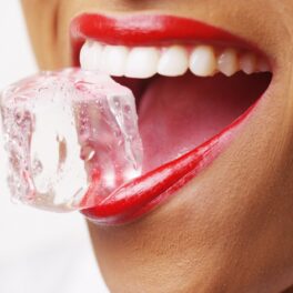 Imagine cu gura unei femei, ruj roșu, cu un cub de gheață între buze, fundal alb. Să spargi gheață între dinți e un obicei nesănătos, susțin specialiștii