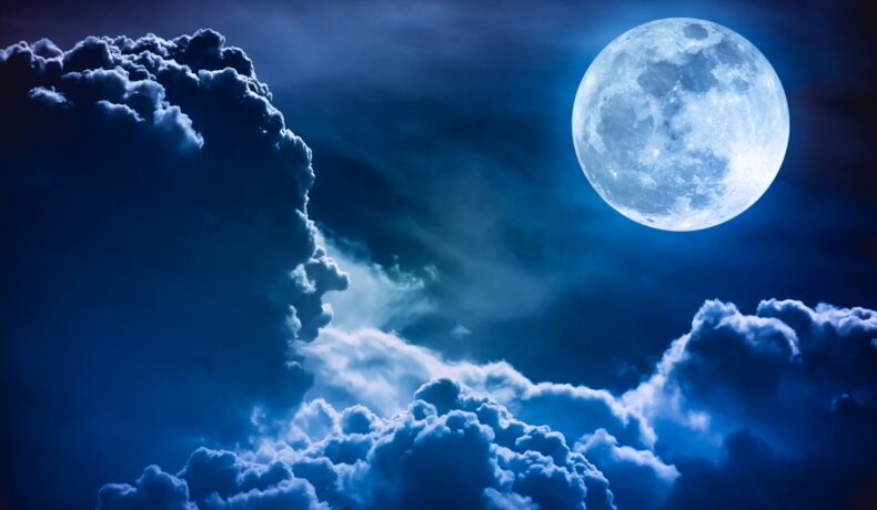 Imagine cu Luna pe cer, în tonuri albastre. Luna e în colțul drept, deasupra norilor. Experții cred că Luna se va ”clătina” în 2030