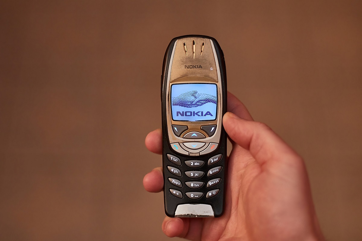 Telefon Nokia 6310 original, pe negru, ținut în mână, cu un fundal bej. Noua variantă Nokia 6310 a fost lansată în anul 2021
