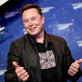 Elon Musk în anul 2020, oe covorul roșu al premiilor Axel Springer. E îmbrăcat într-o geacă neagră de piele, cu tricou negru, pe fundal albastru. Averea lui Elon Musk trece de 200 de miliarde de dolari