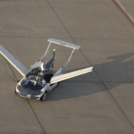 Mașina zburătoare AirCar pe pista unui aeroport, cu aripile deschise