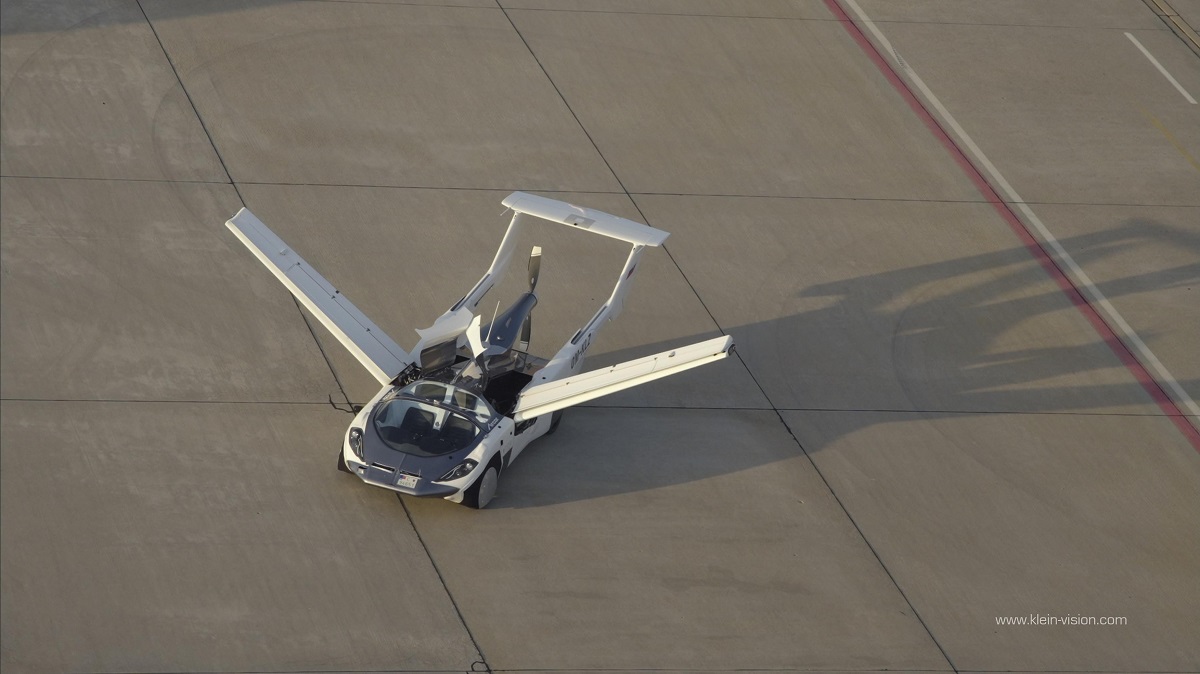 Mașina zburătoare AirCar pe pista unui aeroport, cu aripile deschise
