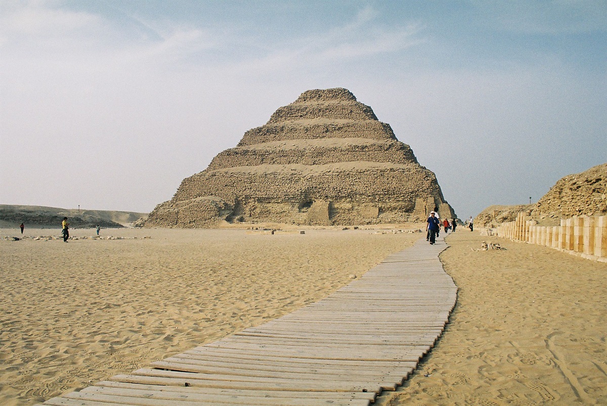 Piramida lui Djoser, din Egipt, fotografiată ziua, lângă un drum de emn. E considerată una dintre cele mai vechi piramide
