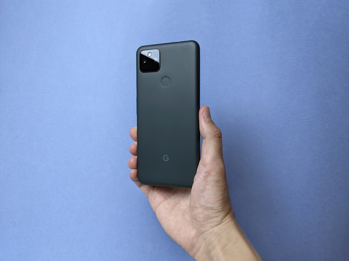 Telefon Google Pixel 5a 5G negru, ținut în mână pe fundal albastru. E una dintre numeroasee alternative Google Pixel 6