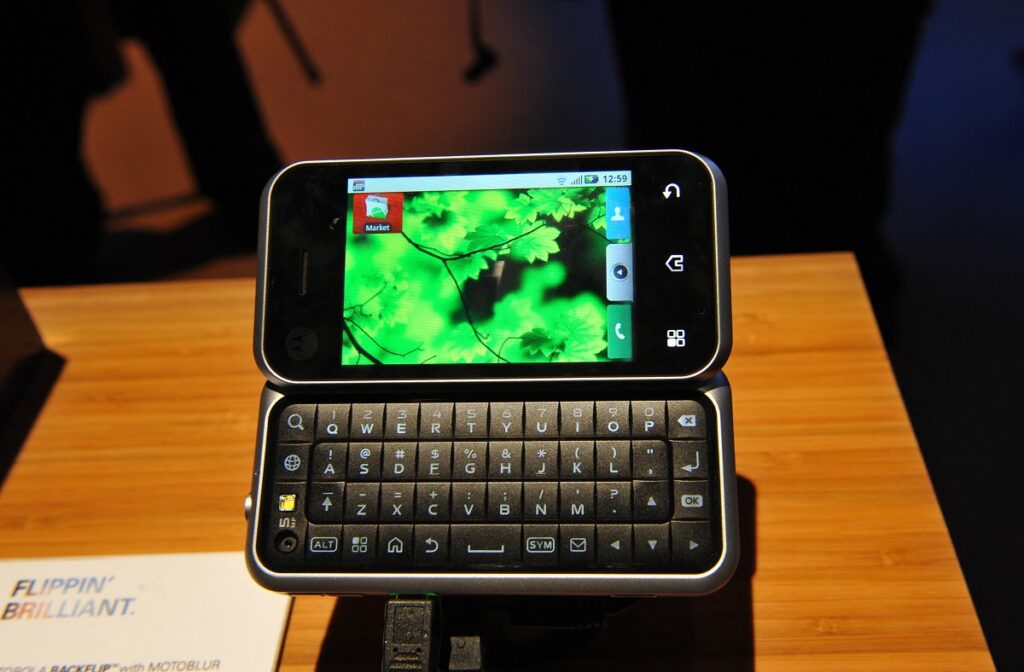 Motorola Backflip, telefon mobil glisant, deschis, pe o masă de lemn, unul dintre cele mai neobișnuite telefoane mobile