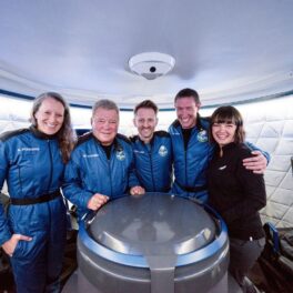 William Shatner fotografiat alături de Audrey Powers, Chris Boshuizen și Glen de Vries. Toți patru poartă uniforma albastră și se țin de mână. William Shatner a ajuns în spațiu la vârsta de 90 de ani