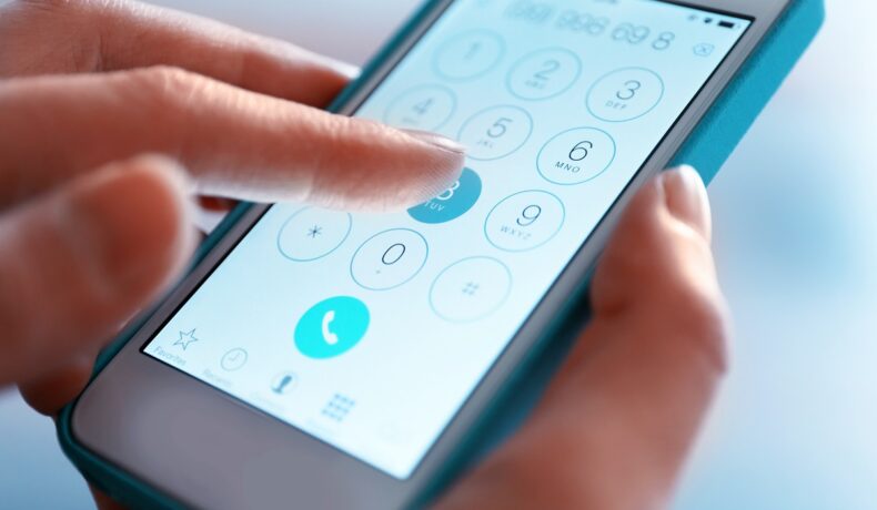Telefon Android în mâna unui utilizator, care folosește tastura de contact. Are ecranul alb și carcasa albastră. Balmuda Phone e considerat cel mai neobișnuit telefon Android al anului pentru că are un design special