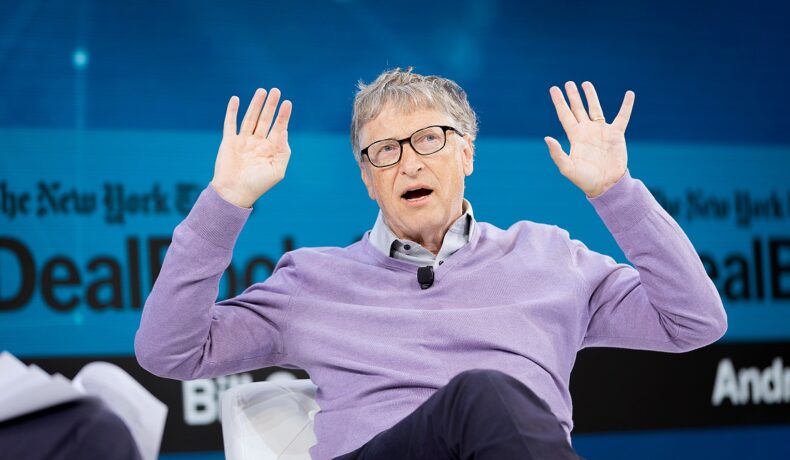 Bill Gates, la un eveniment din anul 2019. E îmbrăcat cu un pulover mov și are albastru pe fundal. Bill Gates ar fi putut avea o avere și mai mare