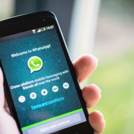 Aplicația WhatsApp pe ecranului unui telefon care e ținut în mână de un utilizator care știe ce e WhatsApp și cum se folosește