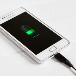 Telefon Samsung Galaxy S2, Android, pe alb, care e la încarcat. Când vine vorba de cum poți verifica starea bateriei telefonului, există câteva trucuri simple