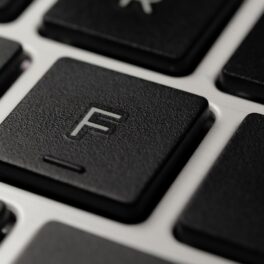 Close-up cu tastatura F, neagră, pe o tastatură cu fundal gri. Mulți se întreabă de ce au tastele f și j mici denivelări