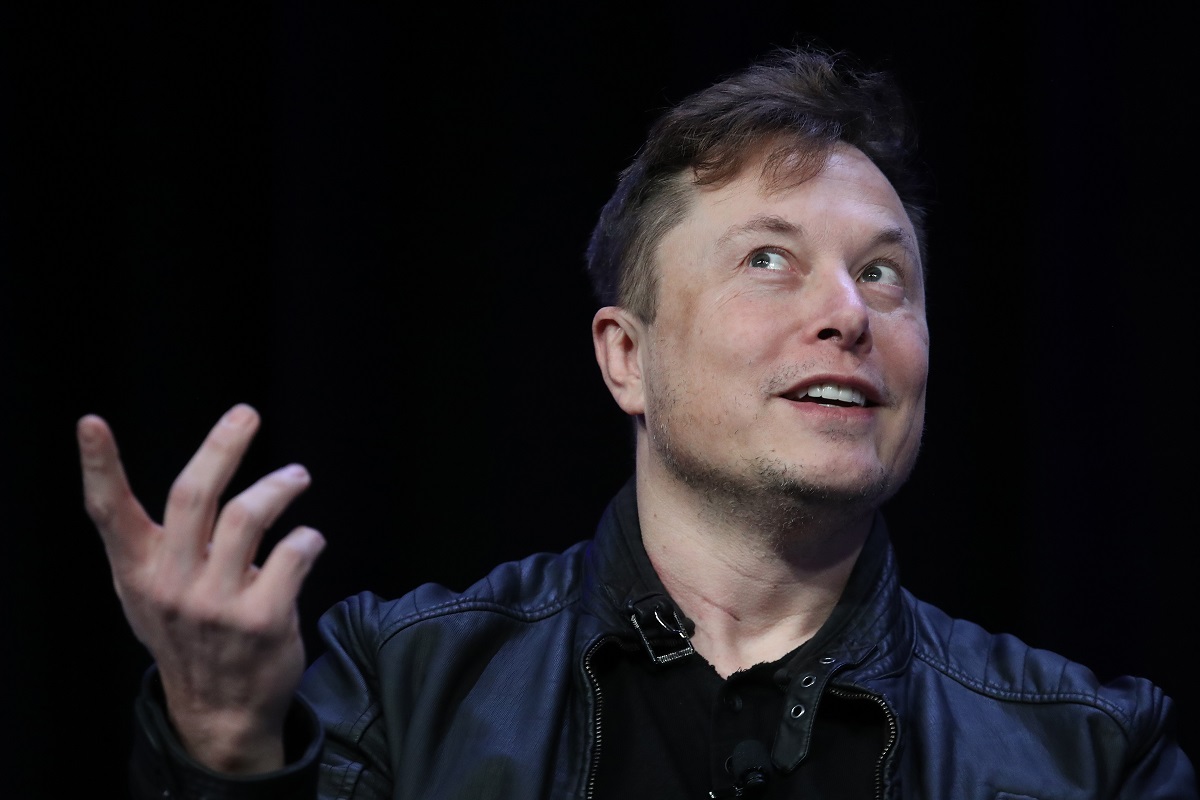 Elon Musk, la o conferință SpaceX din 2020. Poartă un costum negru, cu o cămașă neagră, pe fundal e negru. Elon Musk a vândut milioane de acțiuni Tesla