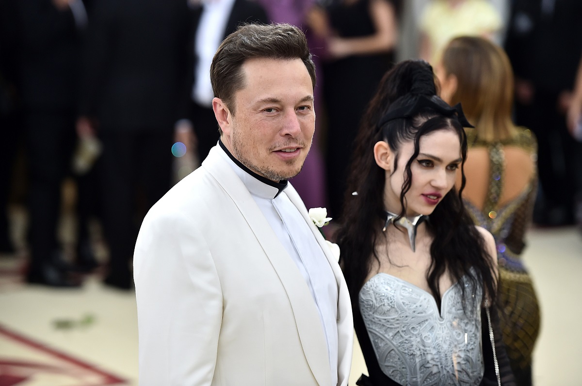 Elon Musk și Grimes pe covorul roșu la Met Gala, în anul 2018. El poartă un costum alb, ea poartă o rochie neagră cu argintiu. Fiul lui Elon Musk cu Grimes are acum 18 luni