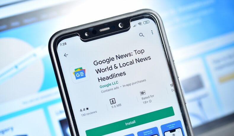 Google News aplicație, în Play Store, pe ecranul unui telefon mobil, cu fundal albastru. Google News revine în Spania în curând