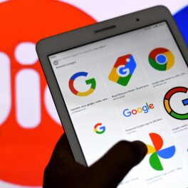 O tabletă pe care se află aplicațiile google în timp ce este ținută în mână în fața unui logo al companiei Jio