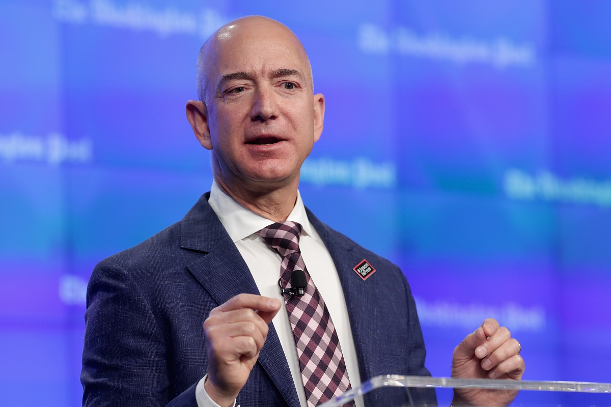 Jeff Bezos, la inaugurarea noii locații a Washington Post, publicaia pe care o deține, în 2016. Poartă un costum albastru, cămașî albă și cravată, cu fundal albastru. Jeff Bezos a donat recent 100 de milioane de dolari pentru Obama Foundation