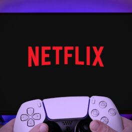 Utilizator care ține un controller alb, în fața unui televizor cu ecran negru, pe care scrie Netflix. Serviciul de gaming Netflix va fi lansat în peste 190 de țări