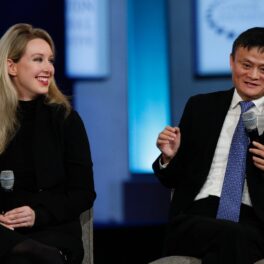 Elizabeth Holmes și Jack Ma, în 2015, la Clinton Global Initiative. Ea e îmbrăcată în negru, el poartă cpstum negru, cămașă albă și cravată albastră