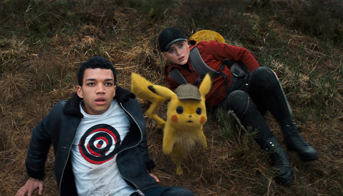 Imagine din filmul Detective Pikachu, lansat în anul 2019. Pikachu poartă o șapcă albastră și stă între doi adolescenți în pădure