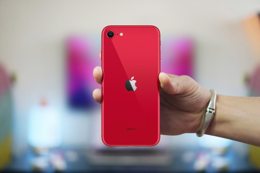 Smartphone Apple iPhone SE 2020, unul dintre cele mai bune smartphone-uri cu prețuri accesibile, cu o carcasă roție, ținut în mână