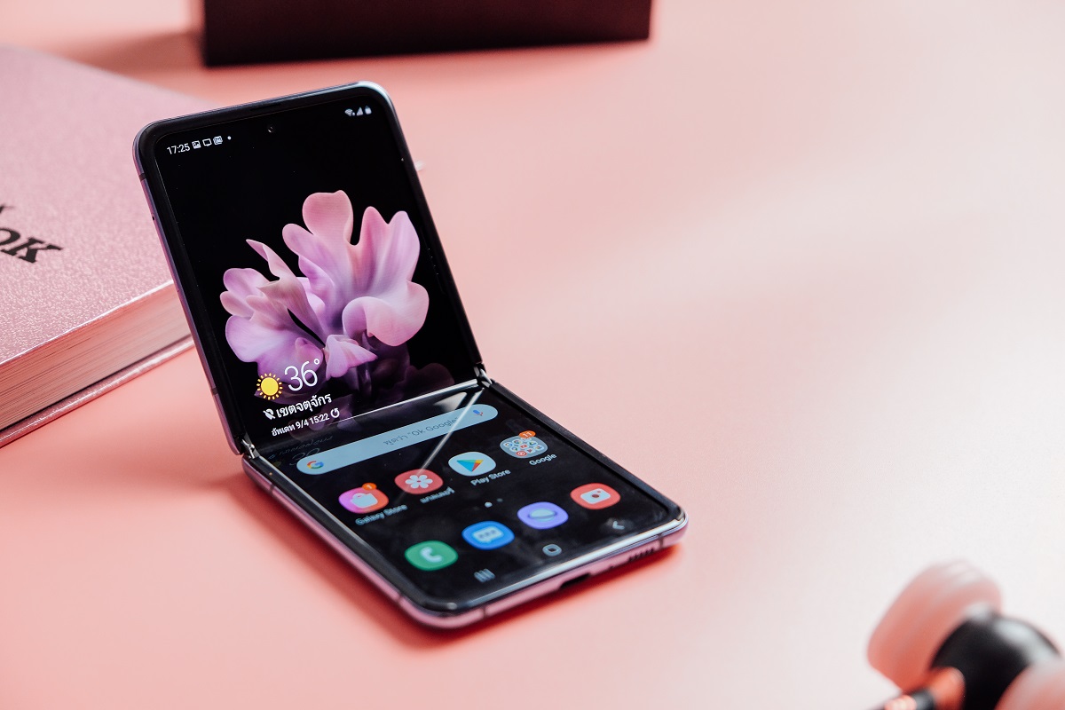 Telefon Galaxy Z Flip, pliat, pe fundal roz. Actualizarea Android 12 One UI 4 a fost lansată recent pe acest dispozitiv