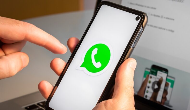 Telefon mobil ținut în mână de un utilizator care are WhatsApp deschis. Există o opțiune atunci când te gândești cum poți schimba numărul de telefon WhatsApp