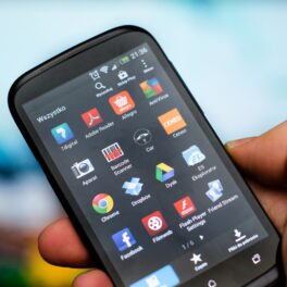 Aplicații pe un telefon Android negru, ținut de un utilizator în mână. Experții au dezvăluit de ce nu trebuie să închizi aplicațiile Android
