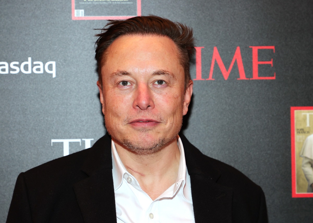Elon Musk, la evenimentul organizat de revista Time, pentru Persoana Anului, în decembrie 2021. Pe covorul roșu, cu fundal negru. Poartă o jachetă neagră, cămașă albă. Elon Musk a fost desemnat Persoana Anului 2021