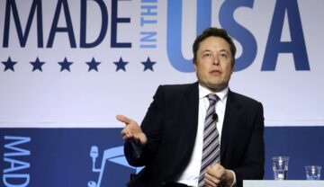 Elon Musk, pe scenă la un eveniment Export-Import Bank, din anul 2014. Poartă un costum negru, cu un fundal alb. Elon Musk susține că va plăti un impozit record în 2021