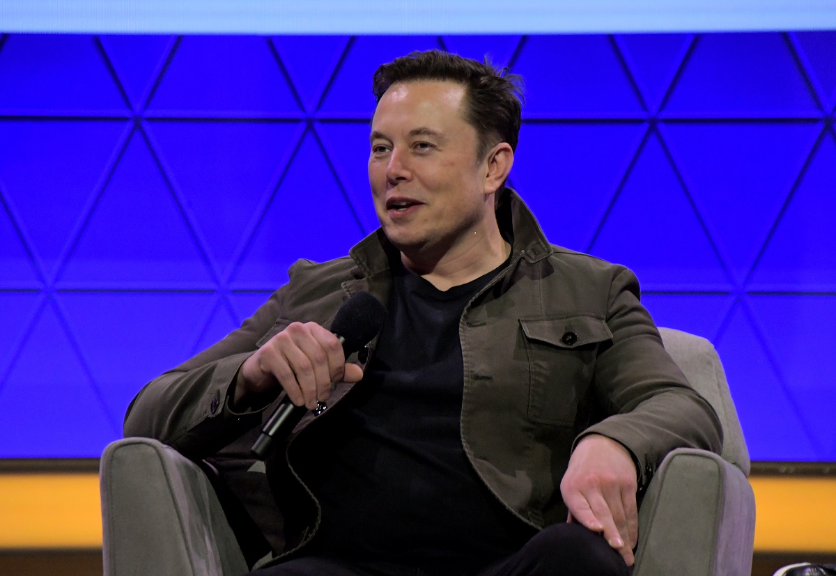Elon Musk, pe scena E3 2019. Stă ântr-un fotoliu gri, are o bluză neagră și un fundal albastru. Elon Musk vrea să creeze combustibil din dioxid de carbon