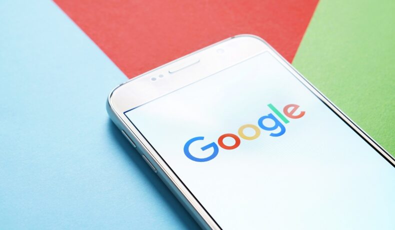 Telefon mobil cu logo-ul Google, pe un fundal cu albastru, roșu și verde. Google nu mai e cel mai accesat site din lume