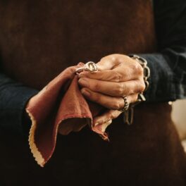 Femeie care ține un inel din aur în mână, pe care îl șlefuiește. Are un design similar cu acel inel din aur descoperit în Israel
