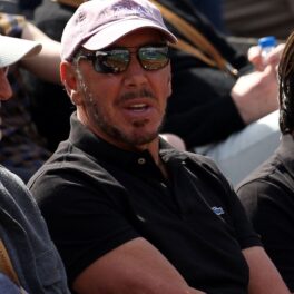 Larry Ellison în public la turneul Paribas Open. Poartă o șapcă și un tricou negru și ochelari de soare