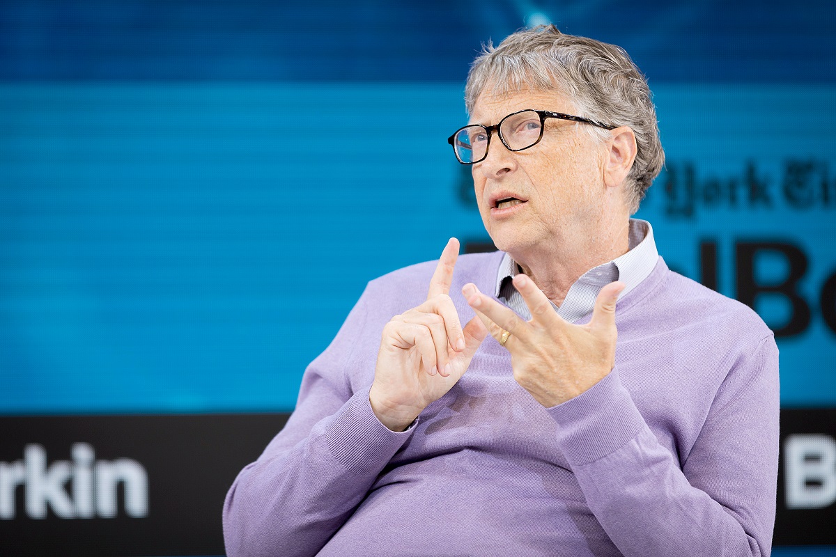 Bill Gates, anul 2019, pe scenă la evenimentul New York Times Dealbook, din New York. Îmbrăcat într-o bluză mov deschis, cu fundal albastru în spate. Bill Gates a vorbit despre planurile lui pentru 2022