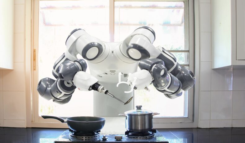Robot alb cu negru, cu două membre, care gătește. Restaurantul robot creat de foști ingineri SpaceX se numește Stellar Pizza