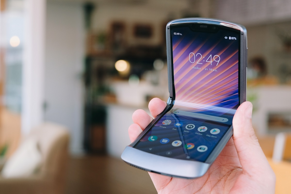 Telefonul Motorola RAZR 5G, lansat în anul 2020, ținut în mână de un utilizator, cu fundal de cameră. Varianta Motorola RAZR 5G nu mai are butonul de Internet