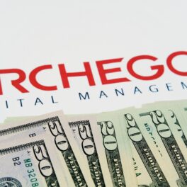 Imagine cu logo-ul Archegos Capital Management, pe fundal alb, cu bancnote de 20 de dolari în partea de jos a imaginii. Bill Hwang a fondat Archegos și a pierdut miliarde de dolari