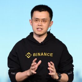 Changpeng Zhao, interviu Bloomberg Television, 2018, în Tokyo, Japonia, pe scenă. Poartă o bluză neagră, cu fundal albastru. Changpeng Zhao a devenit unul dintre cei mai bogați oameni din lume