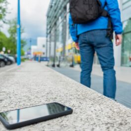 Utilizator care se ridică și uită telefonul negru pe bancă de granit, pe stradă. Dacă te-ai întrebat cum poți găsi telefonul pierdut, experții au câteva soluții