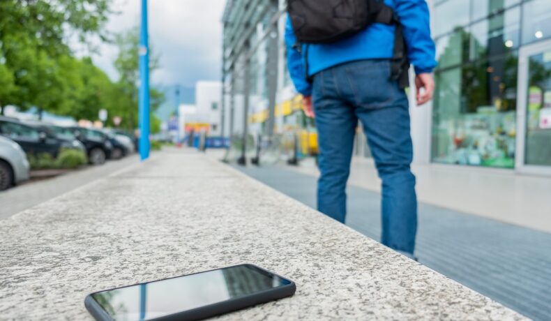 Utilizator care se ridică și uită telefonul negru pe bancă de granit, pe stradă. Dacă te-ai întrebat cum poți găsi telefonul pierdut, experții au câteva soluții