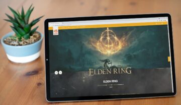 Imagine de pe pagina oficială a jocului Elden Ring pe o tabletă, pe o masă de lemn, cu o plantă pe fundal. Se numără printre numeroasele jocuri video din anul 2022