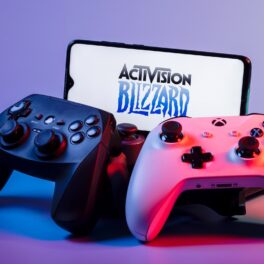 Logo-ul Activision Blizzard, pe ecranul unui teleofn, cu o consolă PlayStation și o consolă Xbox, creată de Microsoft, ce a cumpărat recent compania de gaming