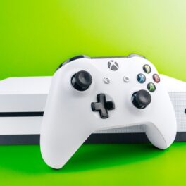 Consola Xbox One, pe alb, pe un fundal verde deschis. Microsoft a oprit recent producția pentru această consolă