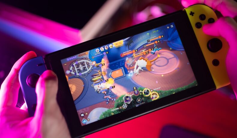 Dispozitiv Nintendo Switch, ținut în mâinile unui utilizator, care joacă Pokémon Unite. Personajele Pokemon Legends Arceus au ajuns pe Internet