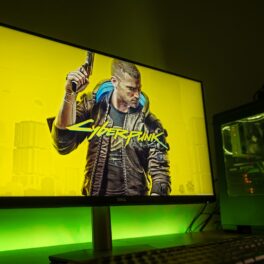 Simbolul jocului Cyberpunk 2077, pe ecranul unui calculator, cu fundal galben, într-o cameră neagră. Prima actualizare Cyberpunk 2077 din 2022 ar putea fi lansată în curând