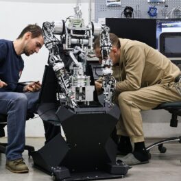 Doi ingineri care lucrează la Robotul umanoid Robo-C-2, ce a uimit cu trăsăturile sale, în Rusia, Vladivostok. Stau pe scaun și studiază robotul