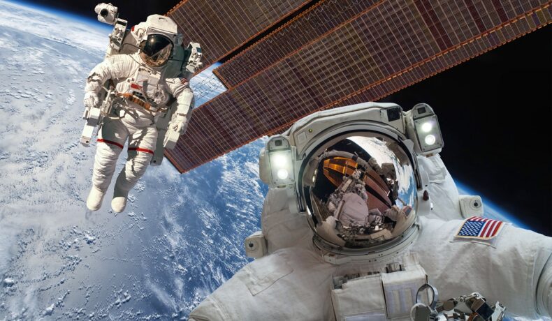 Doi astronauți, lângă Stația Spațială Internațională, în spațiu, cu Pământul pe fundal. Acolo vor ajunge și astronauții amatori care au plătit câte 55 de milioane de dolari pentru misiune