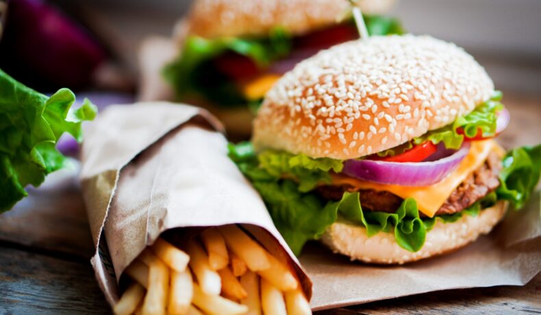 Mâncare fast food, cu burger și cartofi prăjiți, pe un fundal gri. Experții au aflat de ce evită unii oameni mâncarea fast food